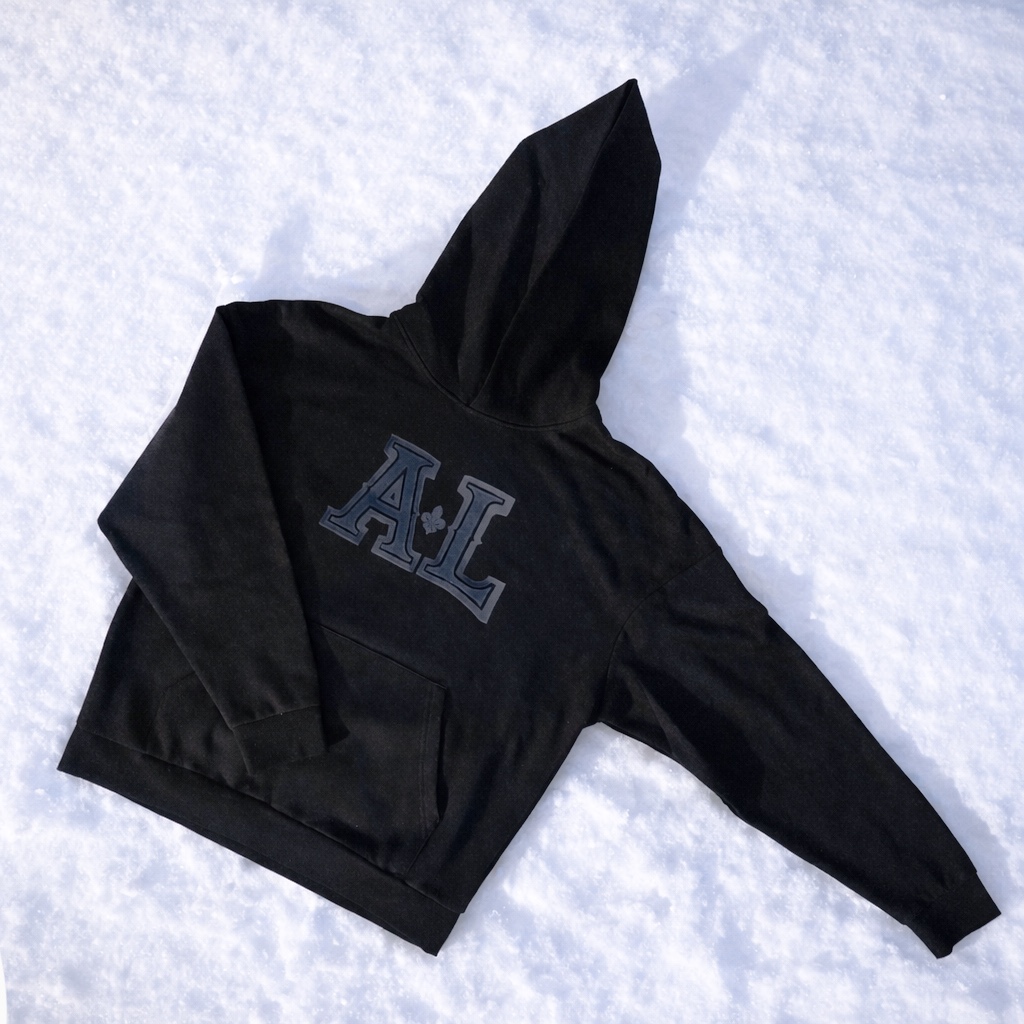 Kangourou noir Arpin Lépine avec logo A·L brodé, posé sur la neige