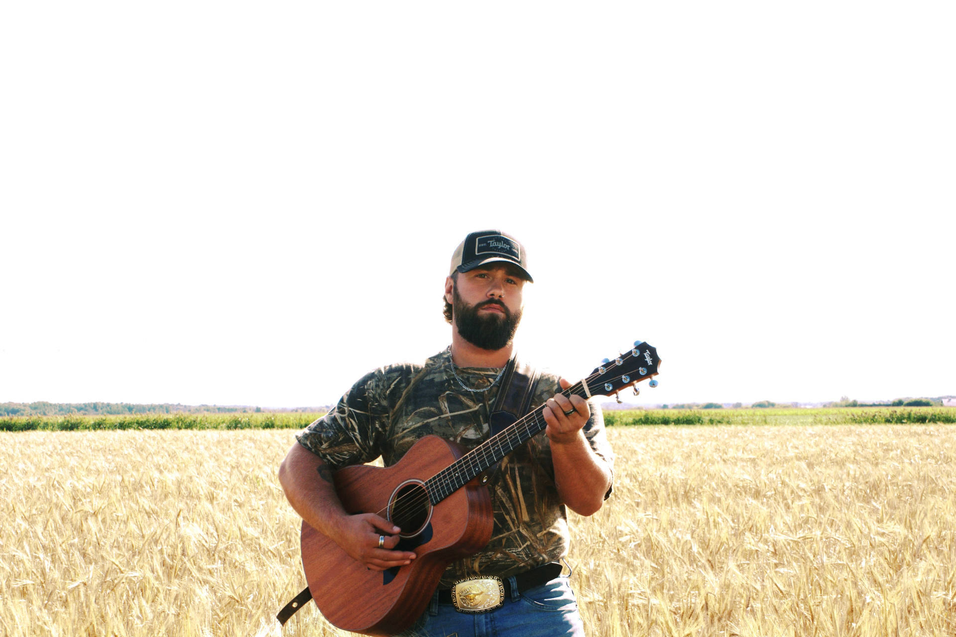 Arpin Lépine dans un champ de blé avec sa guitare